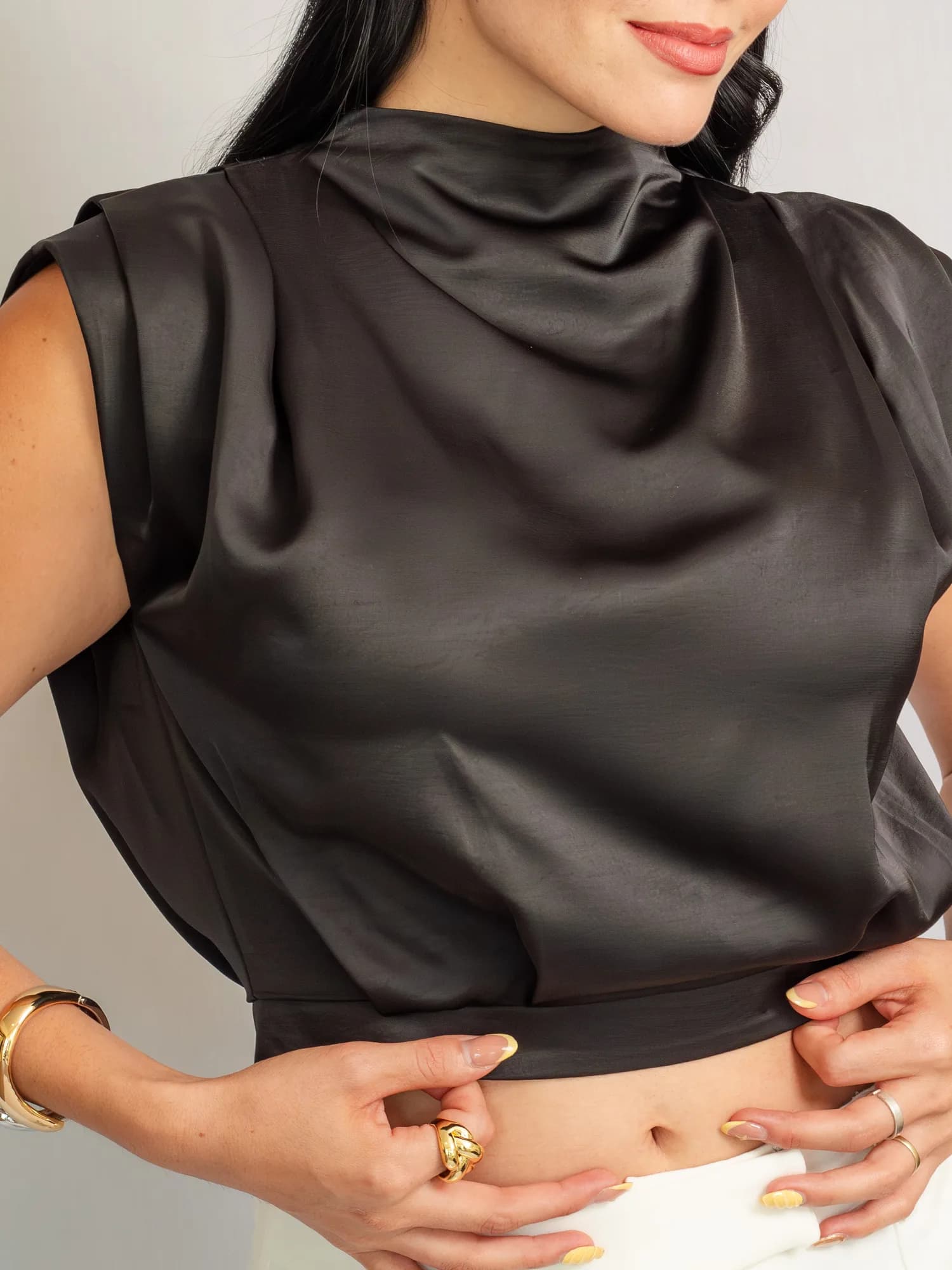 Detalle del drapeado del cuello y el brillo del satín de la blusa negra.